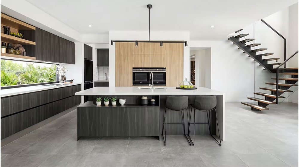 A sleek, contemporary kitchen featuring a central island with seating, wooden cabinetry, minimalist decor, and a staircase leading to the upper level, perfect for modern home living.