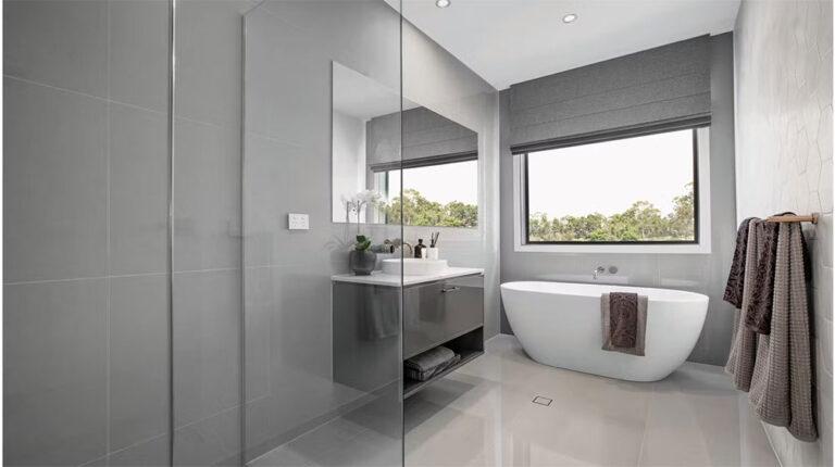 Bright, minimalist bathroom featuring a sleek freestanding bathtub, gray accents, large windows with scenic outdoor views, and contemporary decor for a luxurious, relaxing atmosphere.