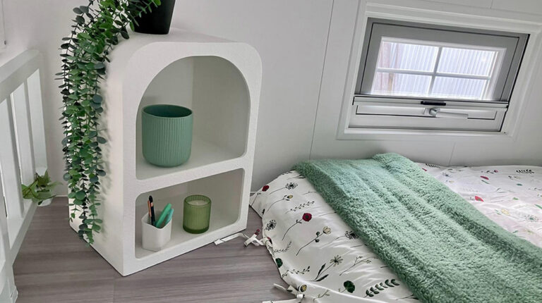 Elegant bedroom with cozy bedding, plush blanket, and stylish shelf with decorative accents, creating a relaxing, peaceful environment perfect for rest and rejuvenation.