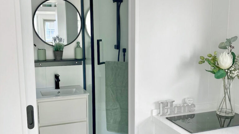 Bright contemporary bathroom featuring a stylish vanity, round mirrors, and a glass shower enclosure with black fixtures for a modern aesthetic.