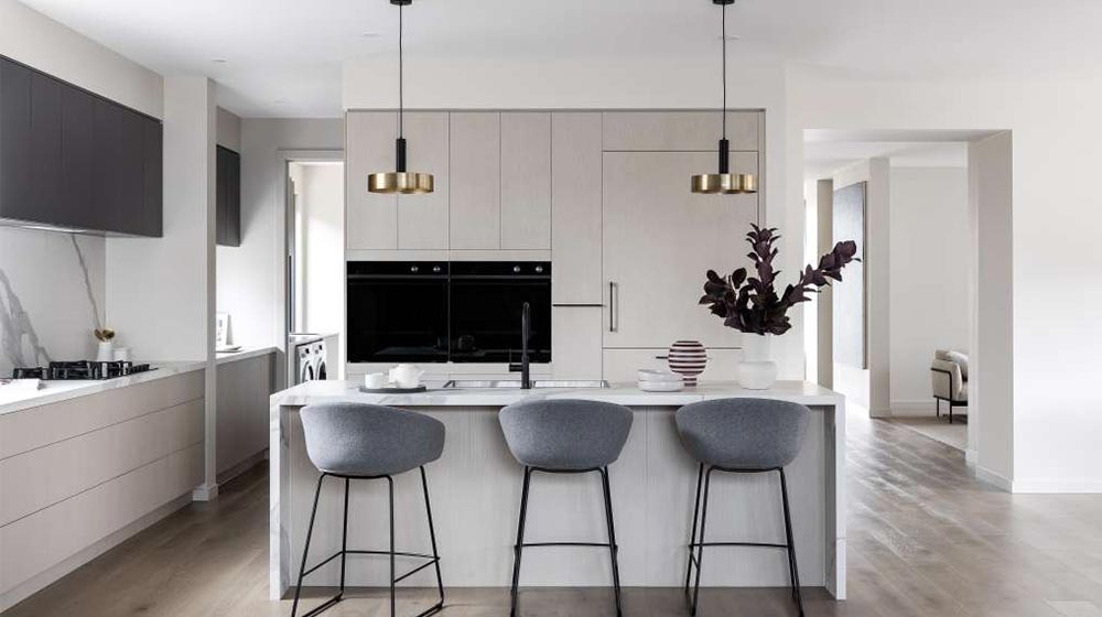 Contemporary kitchen featuring a sleek white design, a stylish breakfast bar with three gray chairs, minimalist cabinetry, and elegant pendant lighting for a sophisticated dining space.