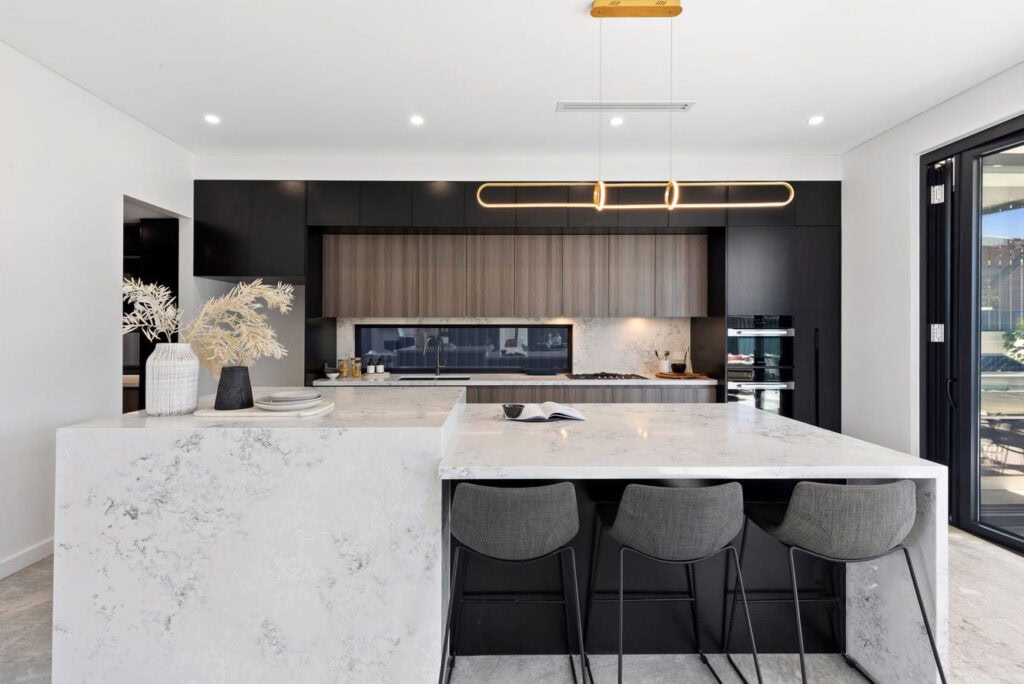 Modern minimalist kitchen featuring sleek black cabinets, a large marble island, and contemporary lighting, perfect for stylish home living and cooking.