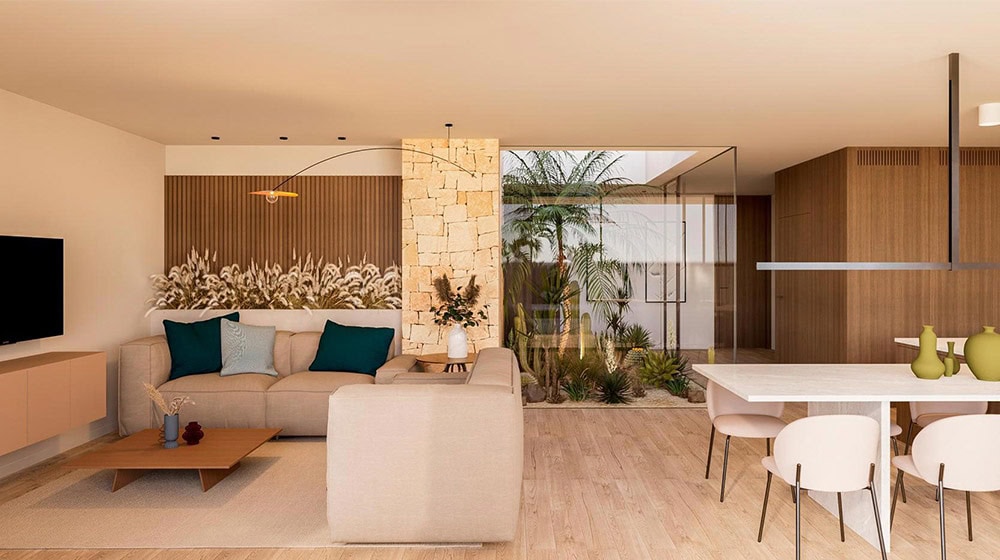 A spacious, contemporary living room in Suva House featuring a neutral color palette, comfortable seating, and large glass doors opening to a lush outdoor garden with palm trees.