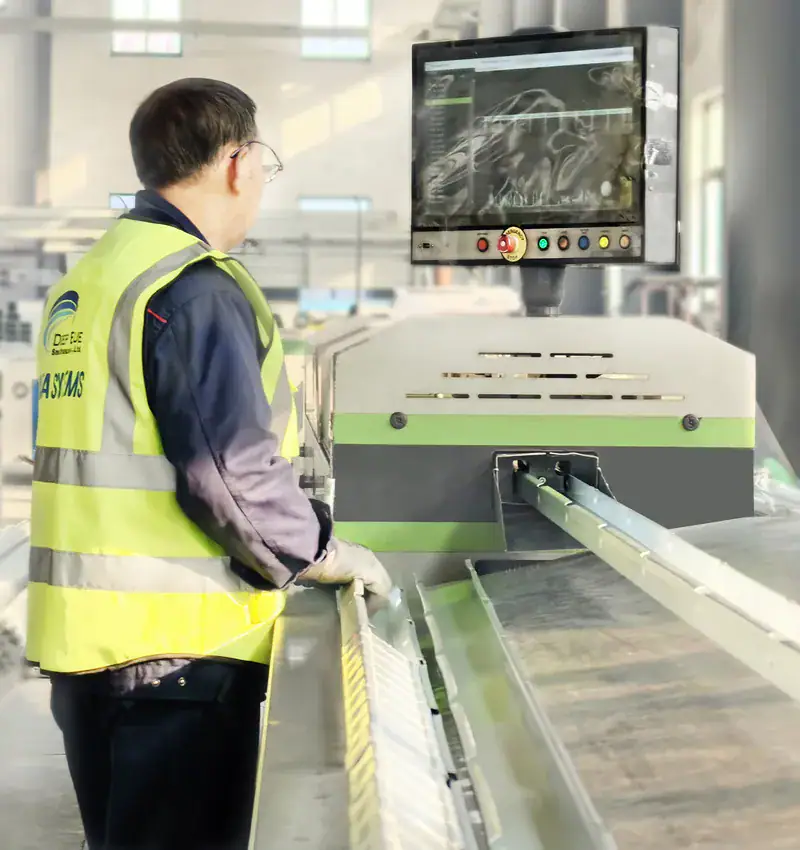 A technician operating a high-tech industrial inspection machine with a monitor displaying detailed analysis, in a modern manufacturing facility.
