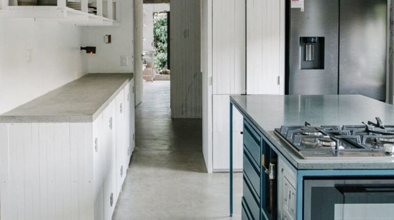 Modern minimalist kitchen with white cabinetry, a sleek island, and stainless steel appliances, creating a clean and contemporary look. Perfect for stylish, functional home cooking spaces.