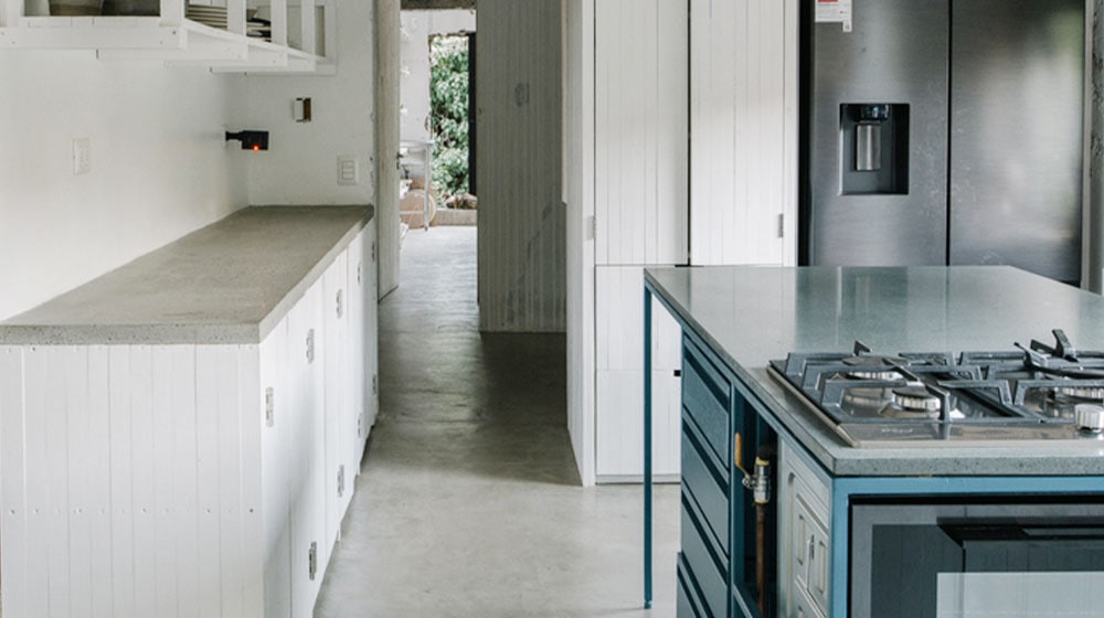 Modern minimalist kitchen with white cabinetry, a sleek island, and stainless steel appliances, creating a clean and contemporary look. Perfect for stylish, functional home cooking spaces.
