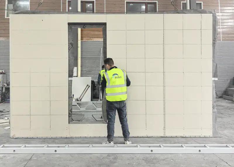 Construction worker installing wall panels at a building site, showcasing modern building techniques and materials.