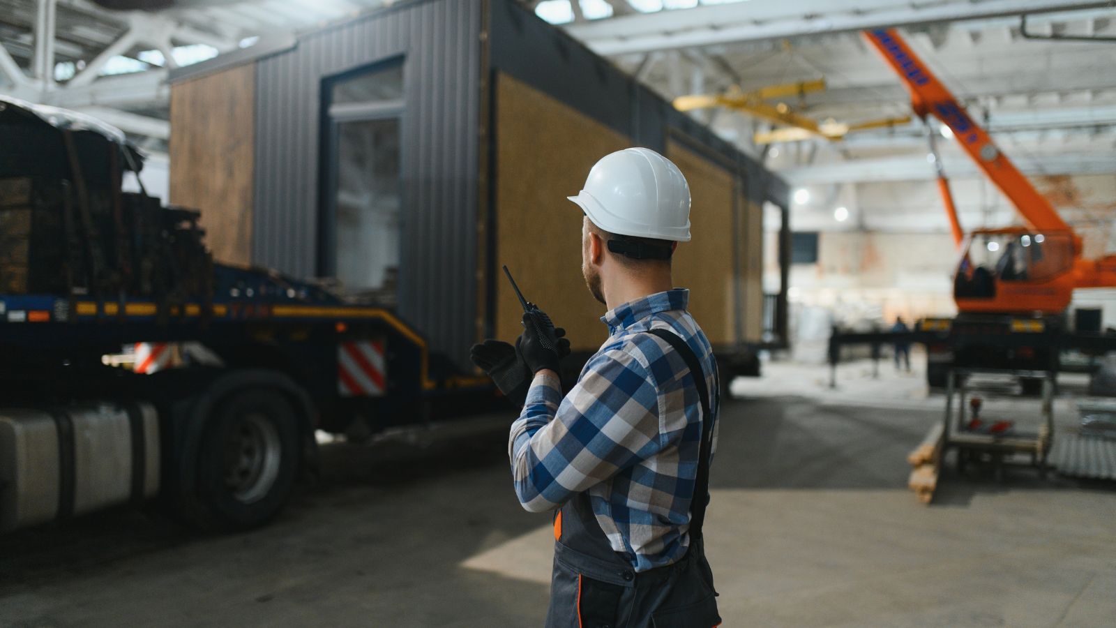 workers loading prefab office module onto flat bed truck for fast transport