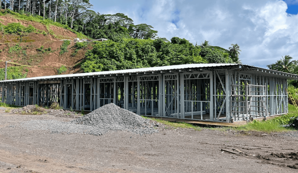 Modern prefab building under construction in lush tropical setting, showcasing rapid assembly and durable design for resilient infrastructure projects.