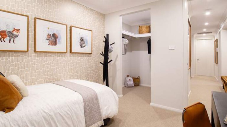Bright bedroom featuring a bed with white linens, framed animal artwork, and a walk-in closet.