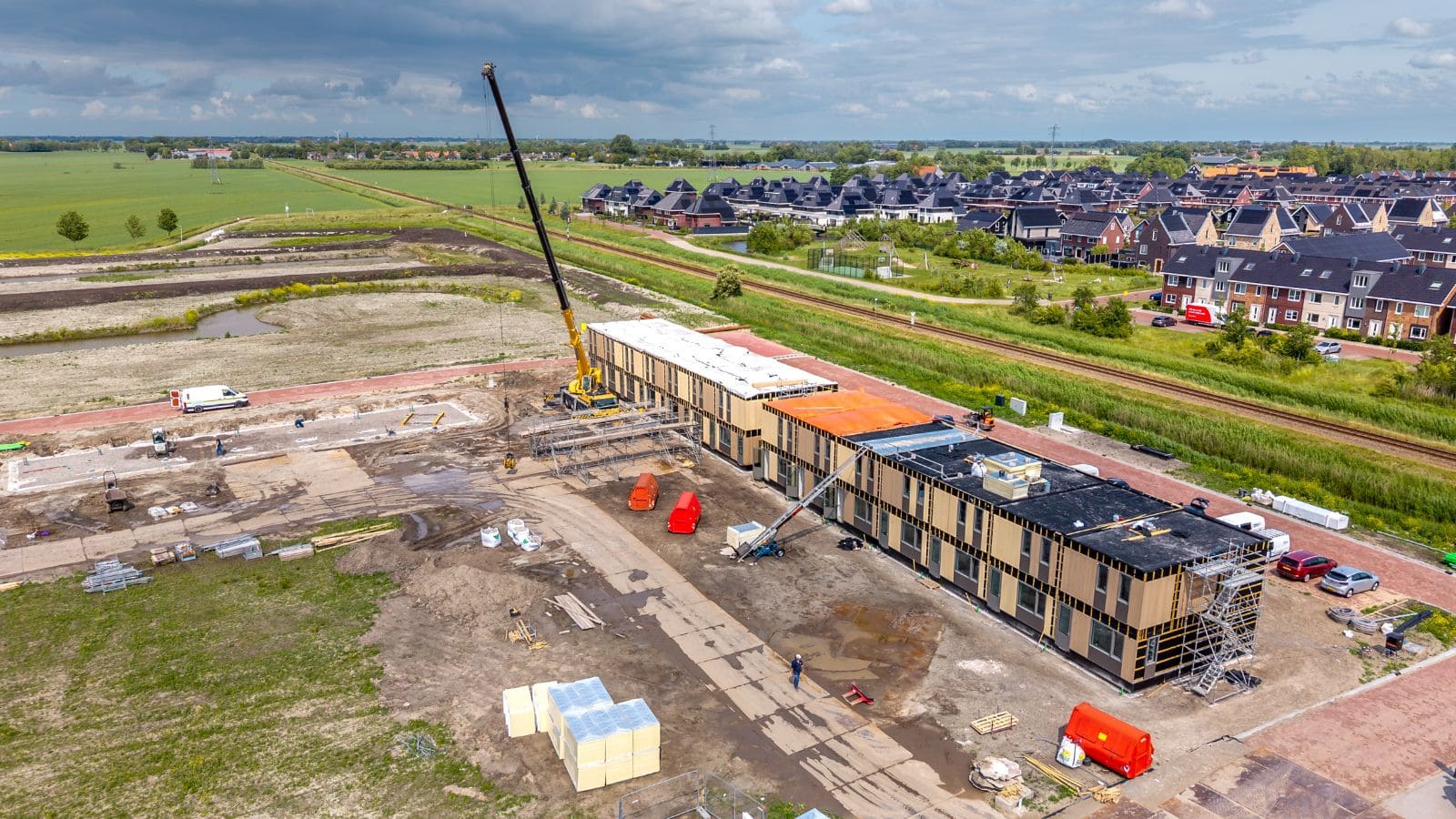 Construction site of a modular home with crane and building materials, showcasing storm-resistant modular housing in progress, emphasizing safety and durability in tornado-prone areas.