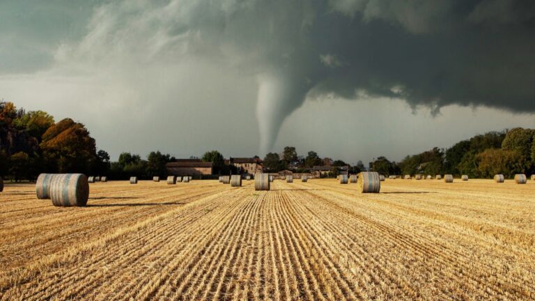 Tornado approaching a rural area with modular homes and hay bales, highlighting storm safety considerations for modular construction during severe weather events.