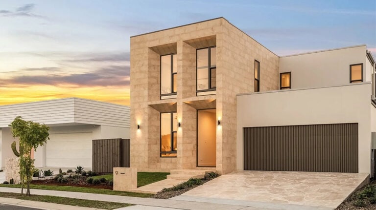 Contemporary residential house with clean lines and modern design, featuring large windows and a spacious driveway, set against a sunset sky.