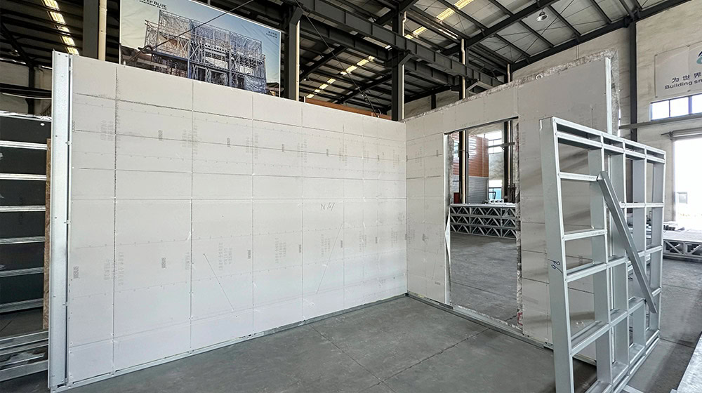 Interior view of a construction site showing a white wall with a window opening and construction materials in an industrial setting.