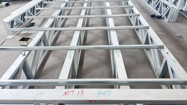 Metal house framework under construction with steel beams and supports, ready for further building stages.