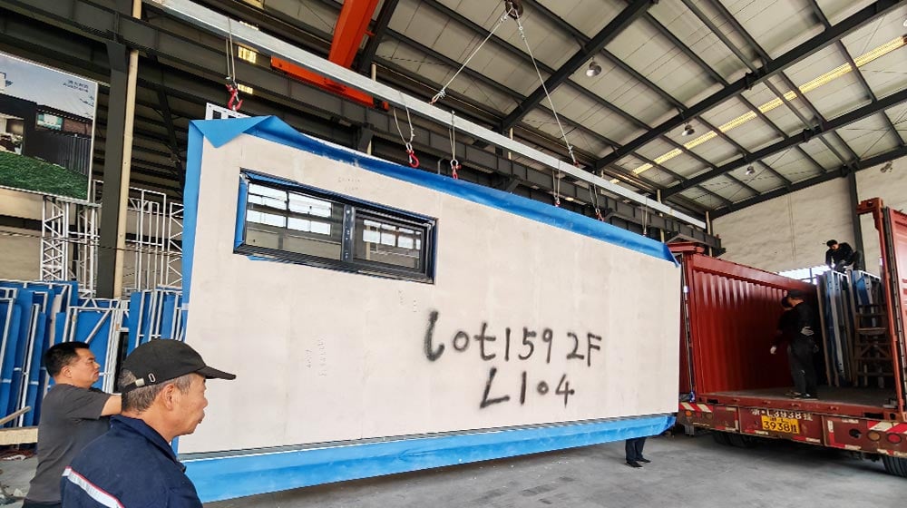 Large prefabricated modular unit being transported inside a factory, with workers observing, showcasing advanced construction technology by Deepblue.
