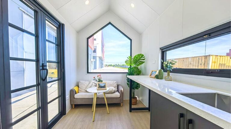 Bright modern kitchen with large windows, a cozy seating area with a sofa, and stylish decor, perfect for a contemporary home.