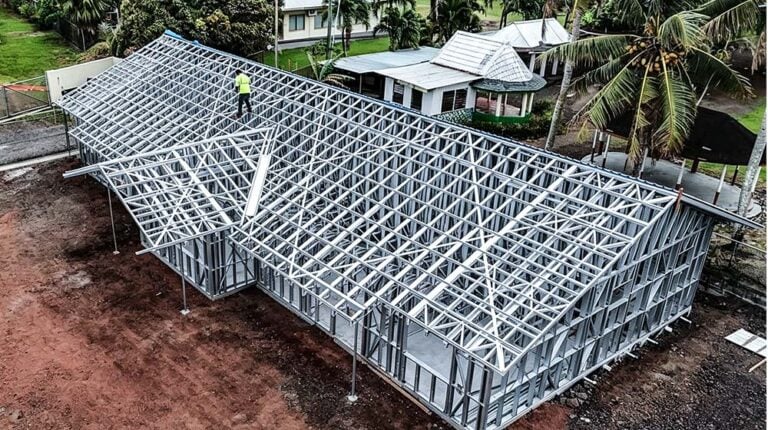 Stahlrahmenkonstruktion einer im Bau befindlichen Villa, während ein Arbeiter die Baustelle inspiziert; zeigt ein langlebiges Fertighaus-Design nach US-Standard.