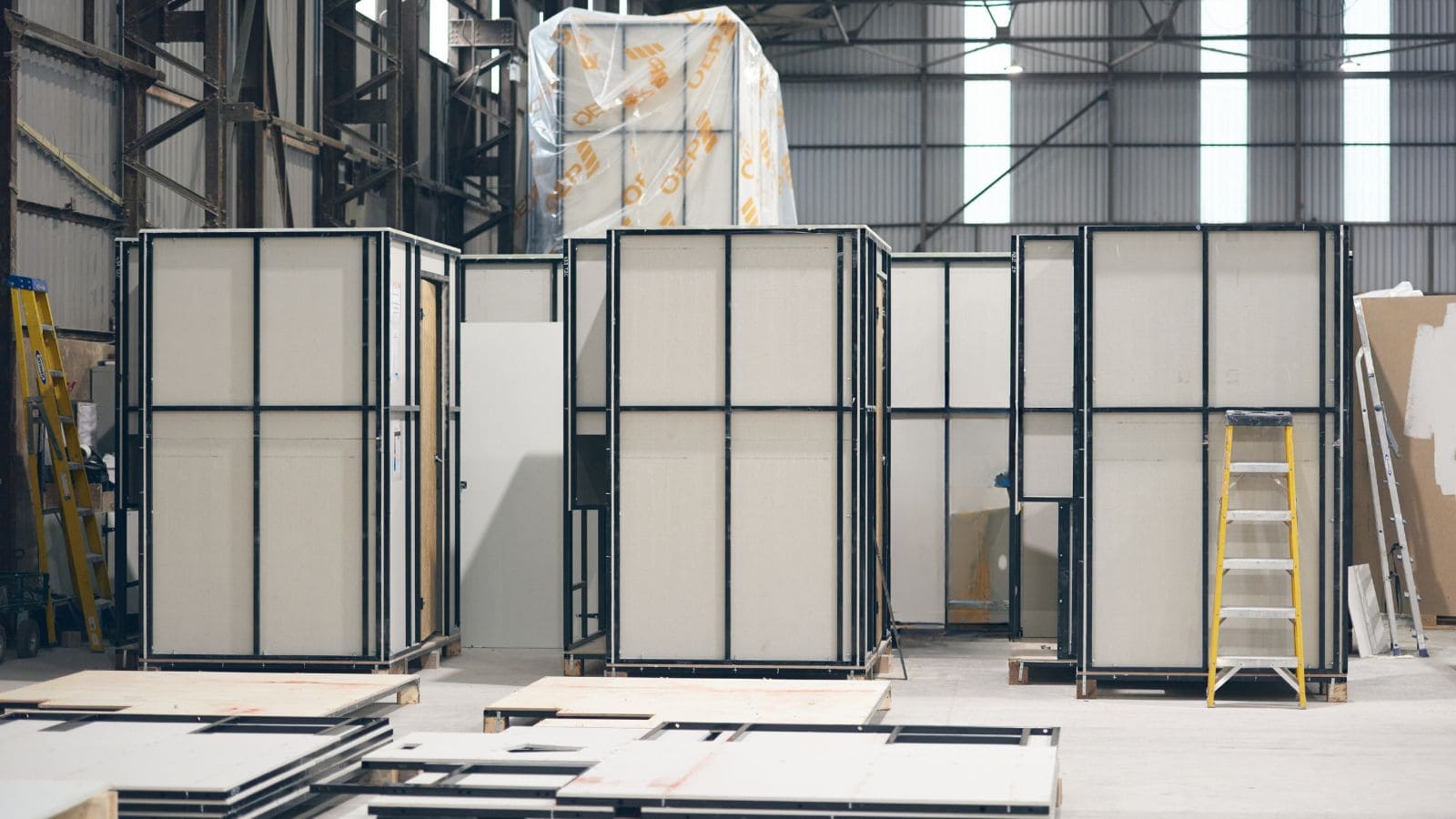 Pre-fabricated modular hotel construction units in a warehouse setting, ready for assembly, showcasing modern building techniques for efficient hotel development.