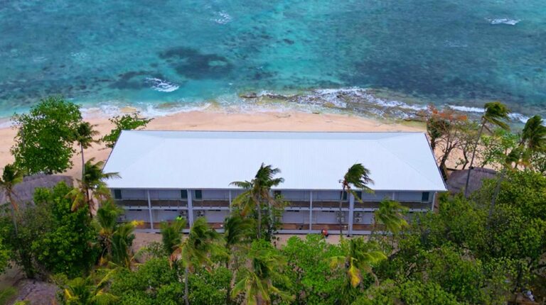 Ein Strandhotel auf Fidschi mit einer leichten Stahlrahmenkonstruktion, umgeben von üppigem Grün und mit Blick auf das klare blaue Meer, ideal für Urlaubsaufenthalte.